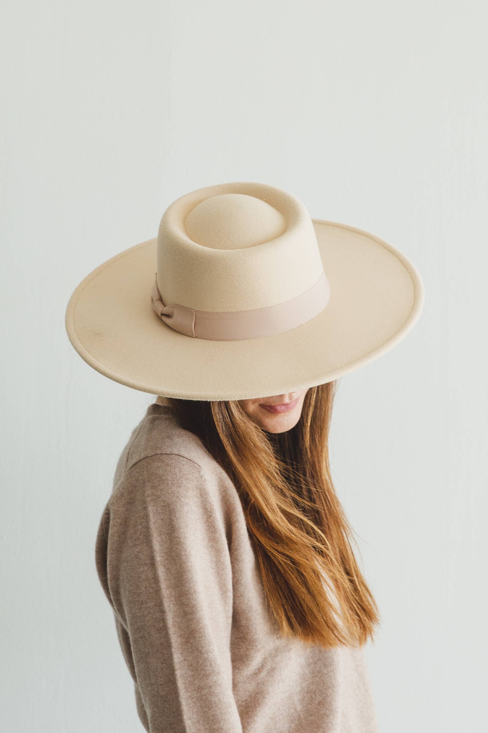 Person wearing a beige wide-brimmed hat on a plain background