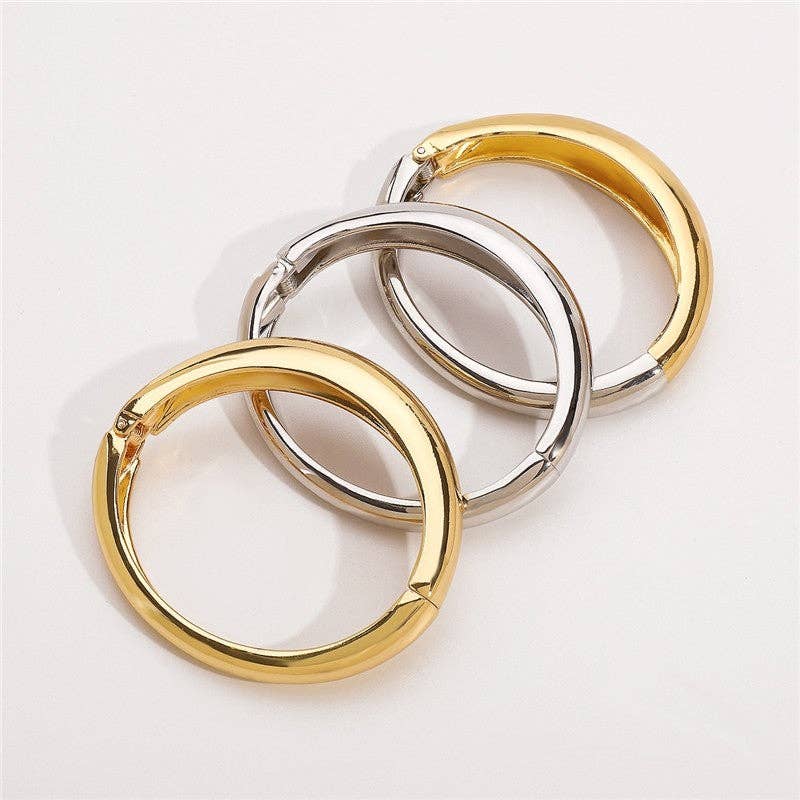 Two hoop earrings, one gold and one silver, on a white background