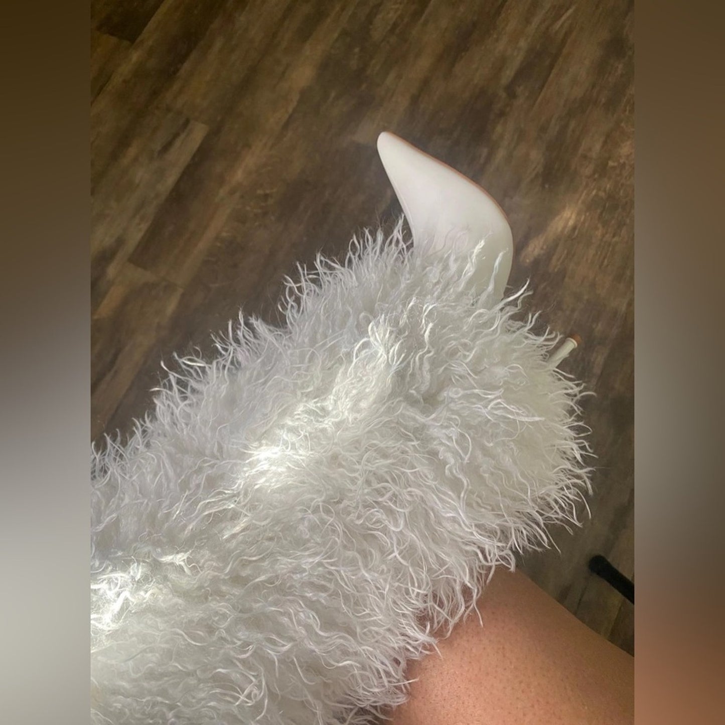 Close-up of a white feathered object with a pointed tip on a wooden surface.