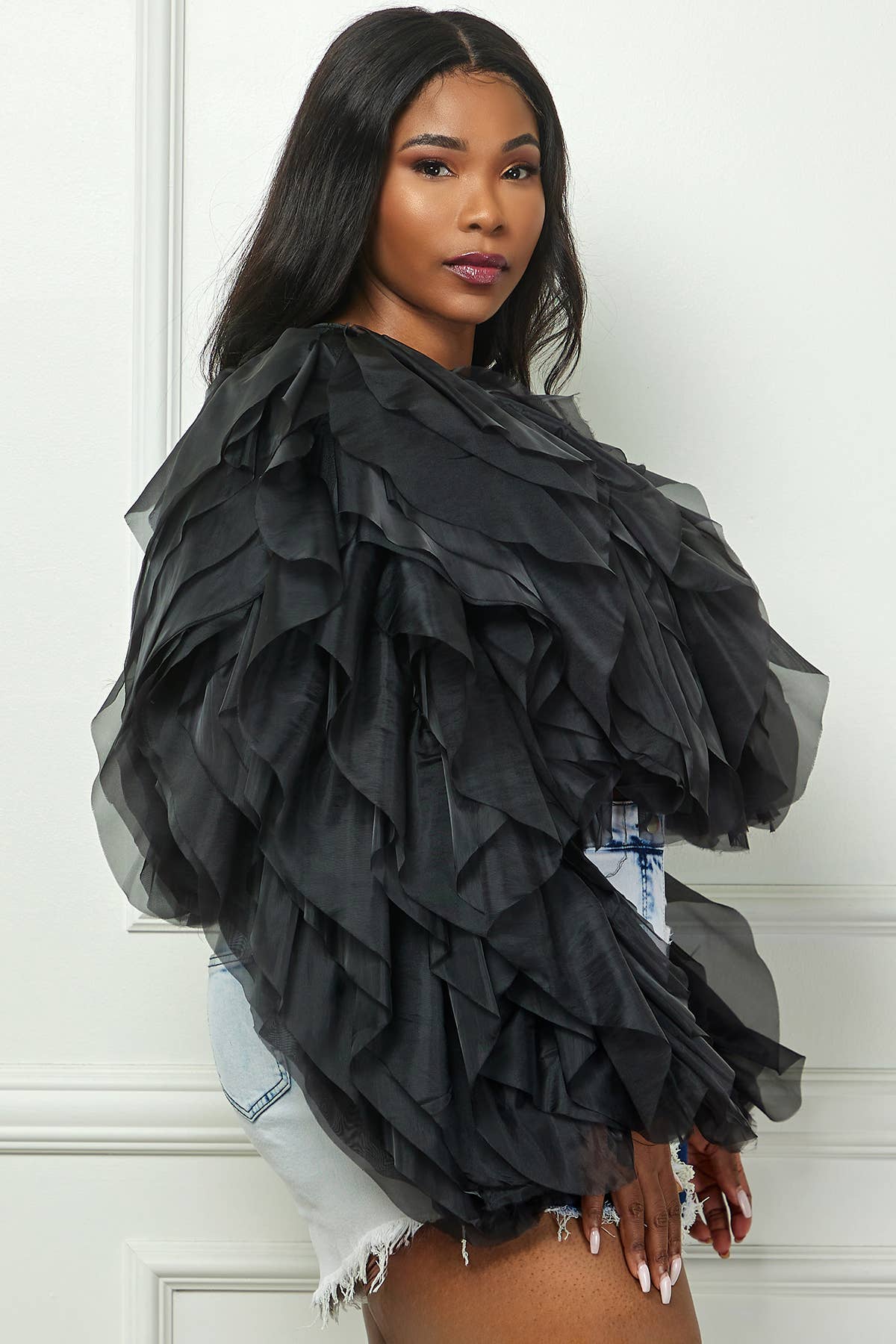 Woman wearing a black ruffled top with a white background