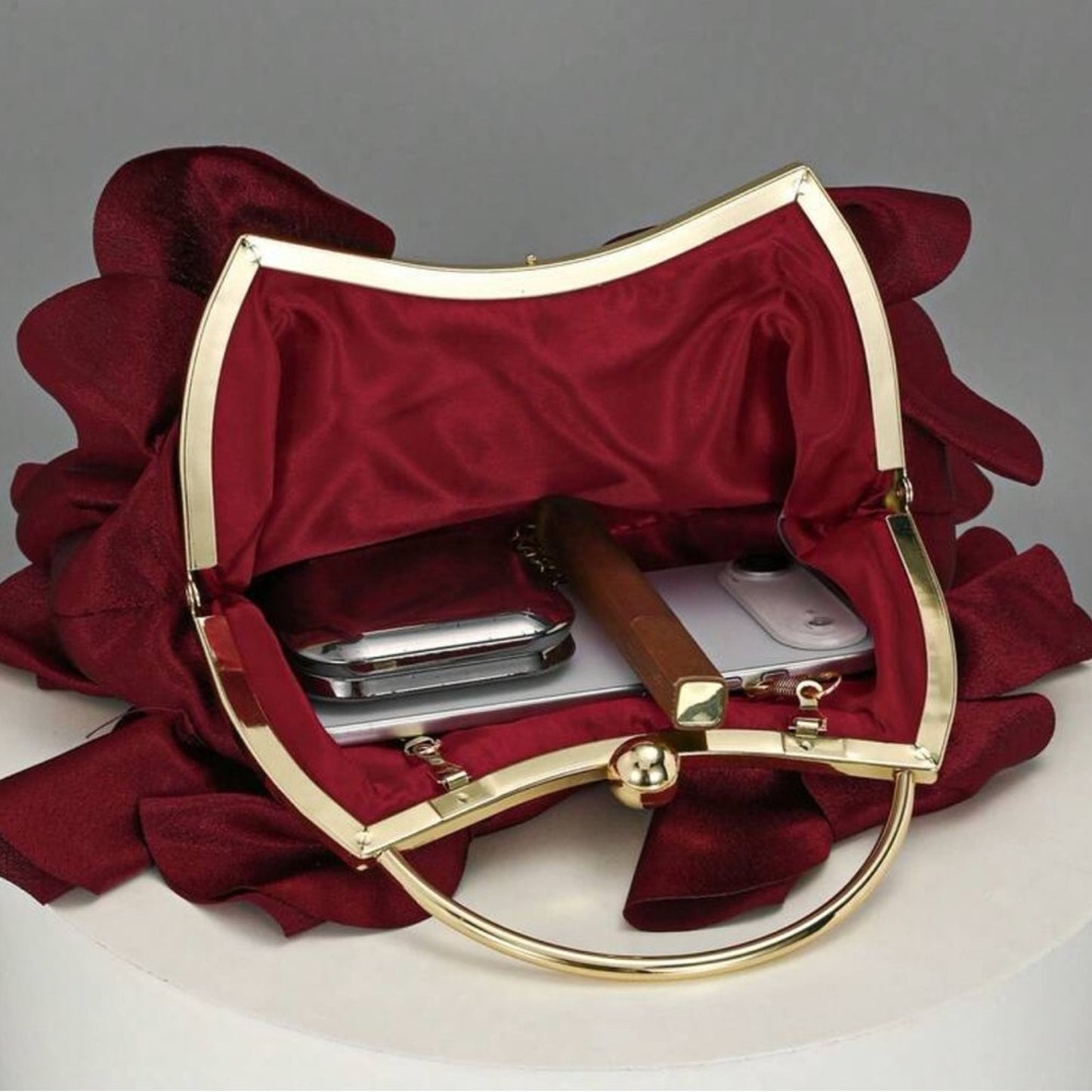Red handbag with gold handle and trim on a gray background