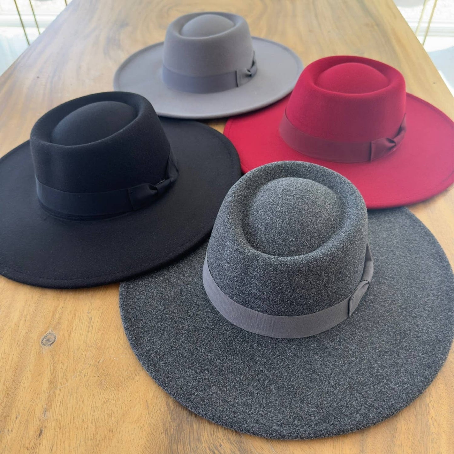 Four hats in black, gray, red, and blue on a wooden surface