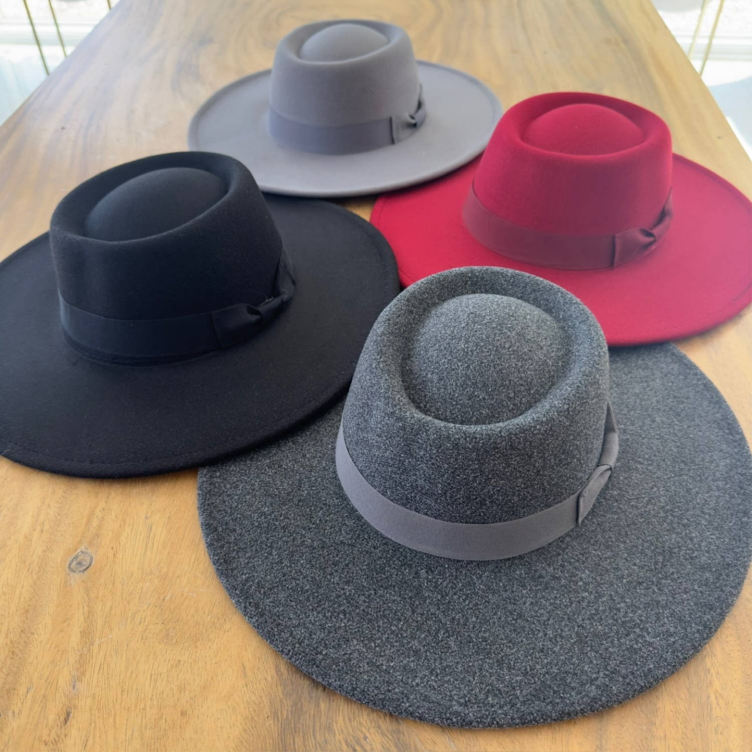 Four hats in black, gray, red, and blue on a wooden surface
