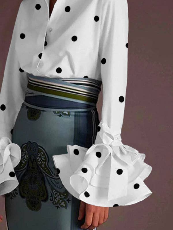 White blouse with black polka dots and sheer sleeves over a blue dress with intricate design.