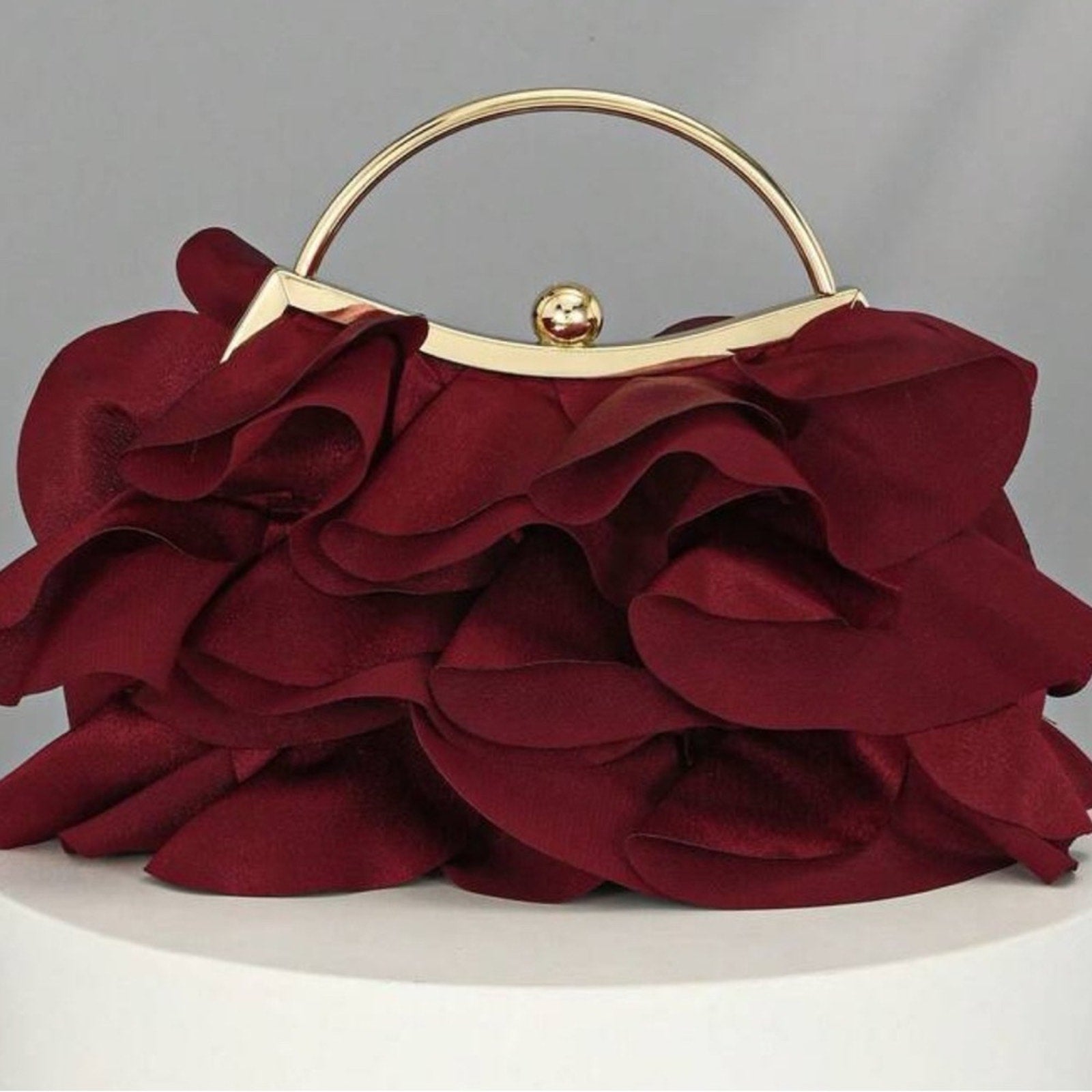 Red floral clutch with gold handle on a gray background