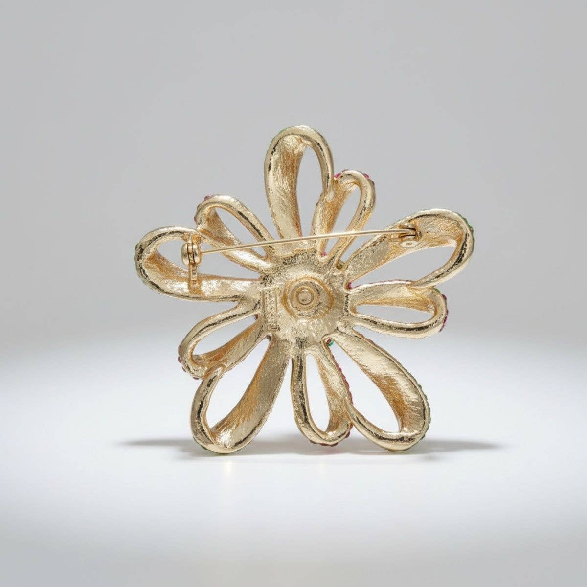 Gold flower-shaped brooch on a light gray background