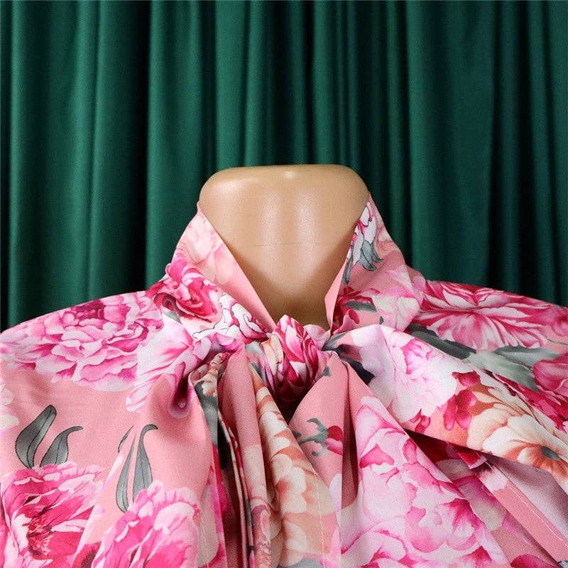 Mannequin wearing a pink floral coat against a green curtain background