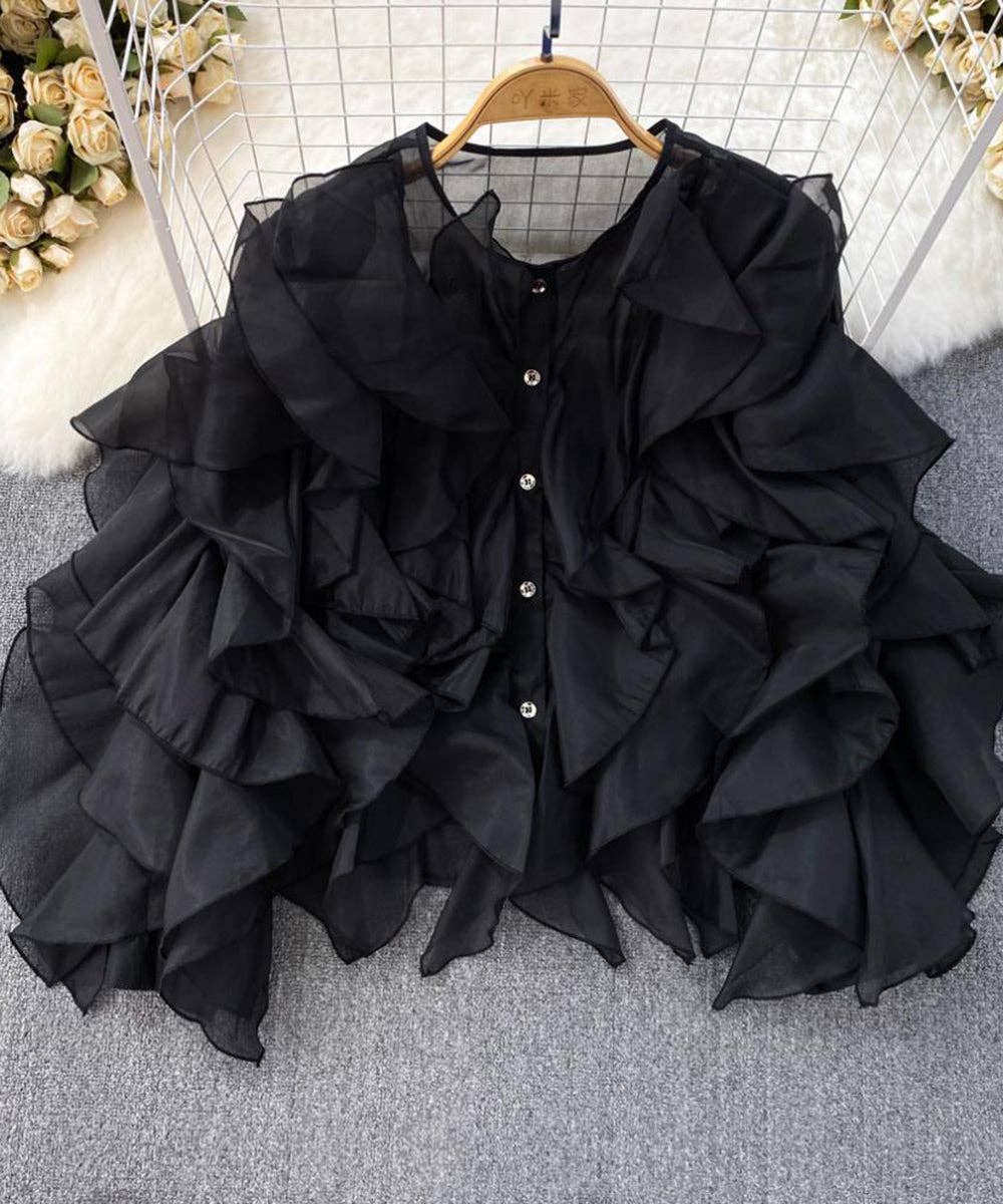 Black ruffled blouse on a hanger with a neutral background