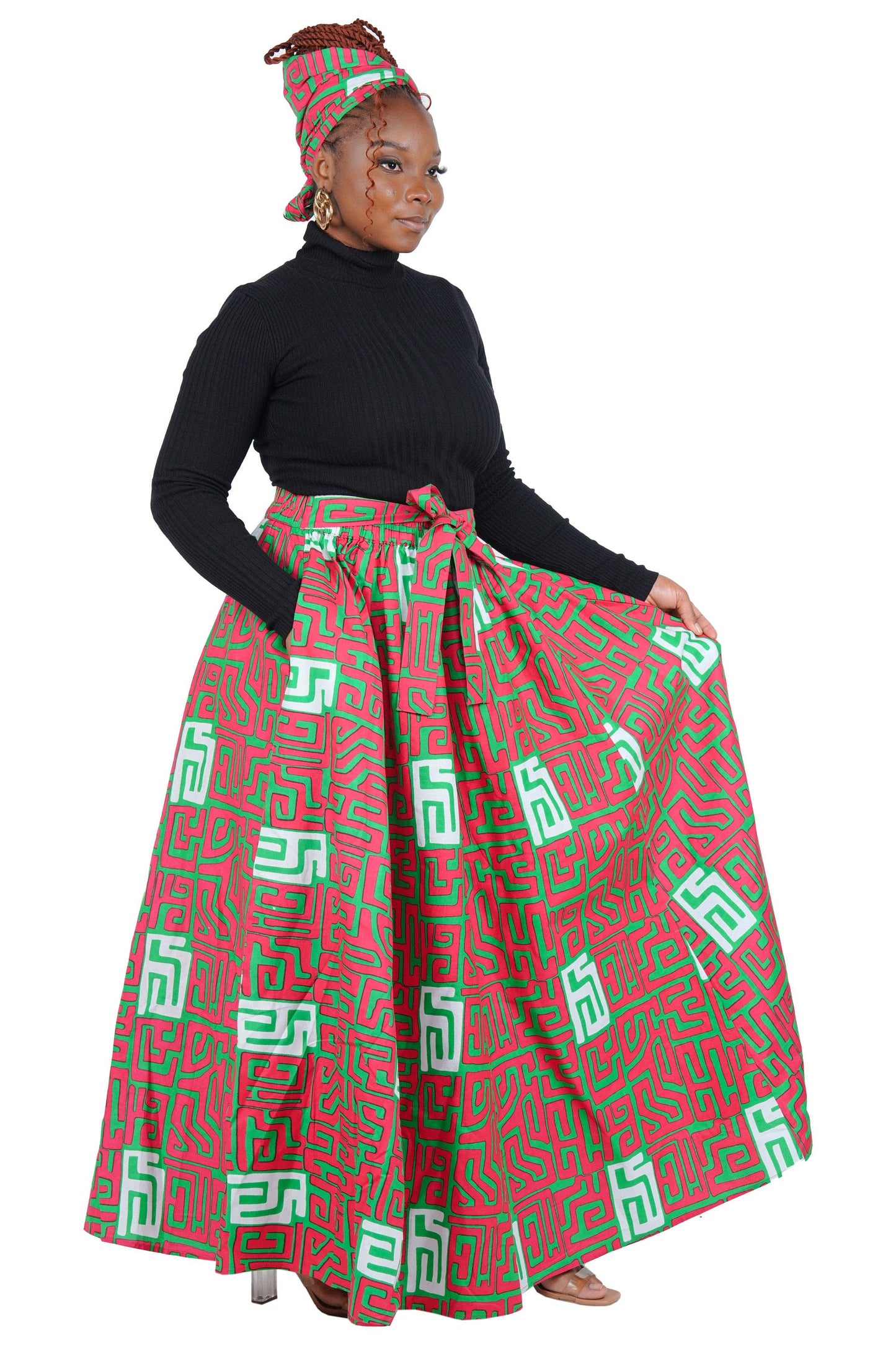 Woman wearing a red and green patterned skirt with a black top on a white background