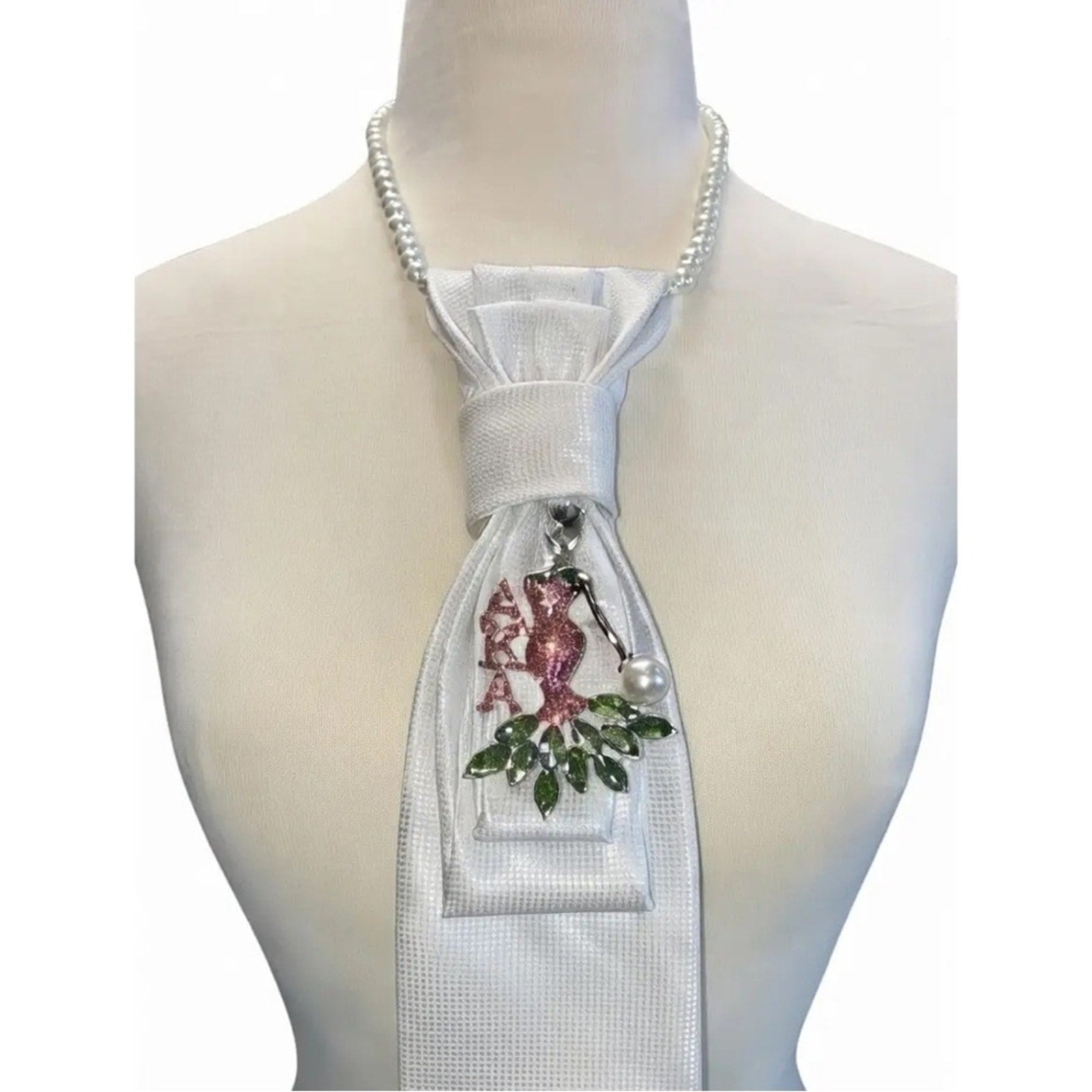 White tie with floral design and brooch on a mannequin against a white background