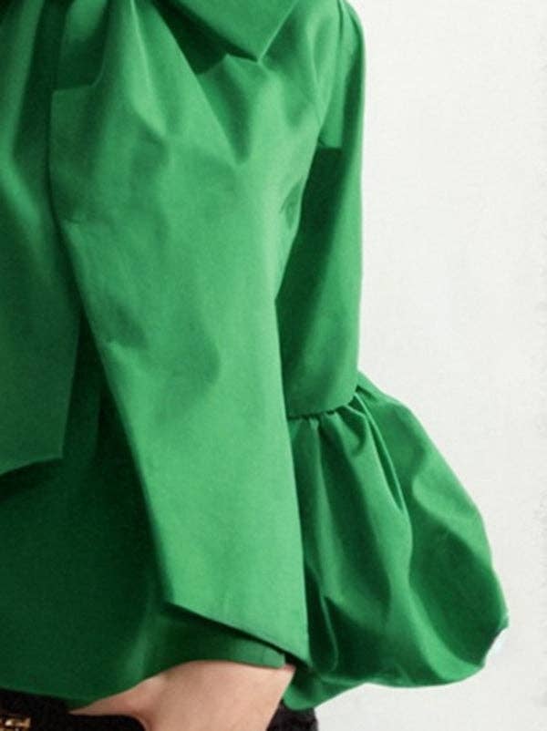 Close-up of a green dress with puffed sleeves on a white background