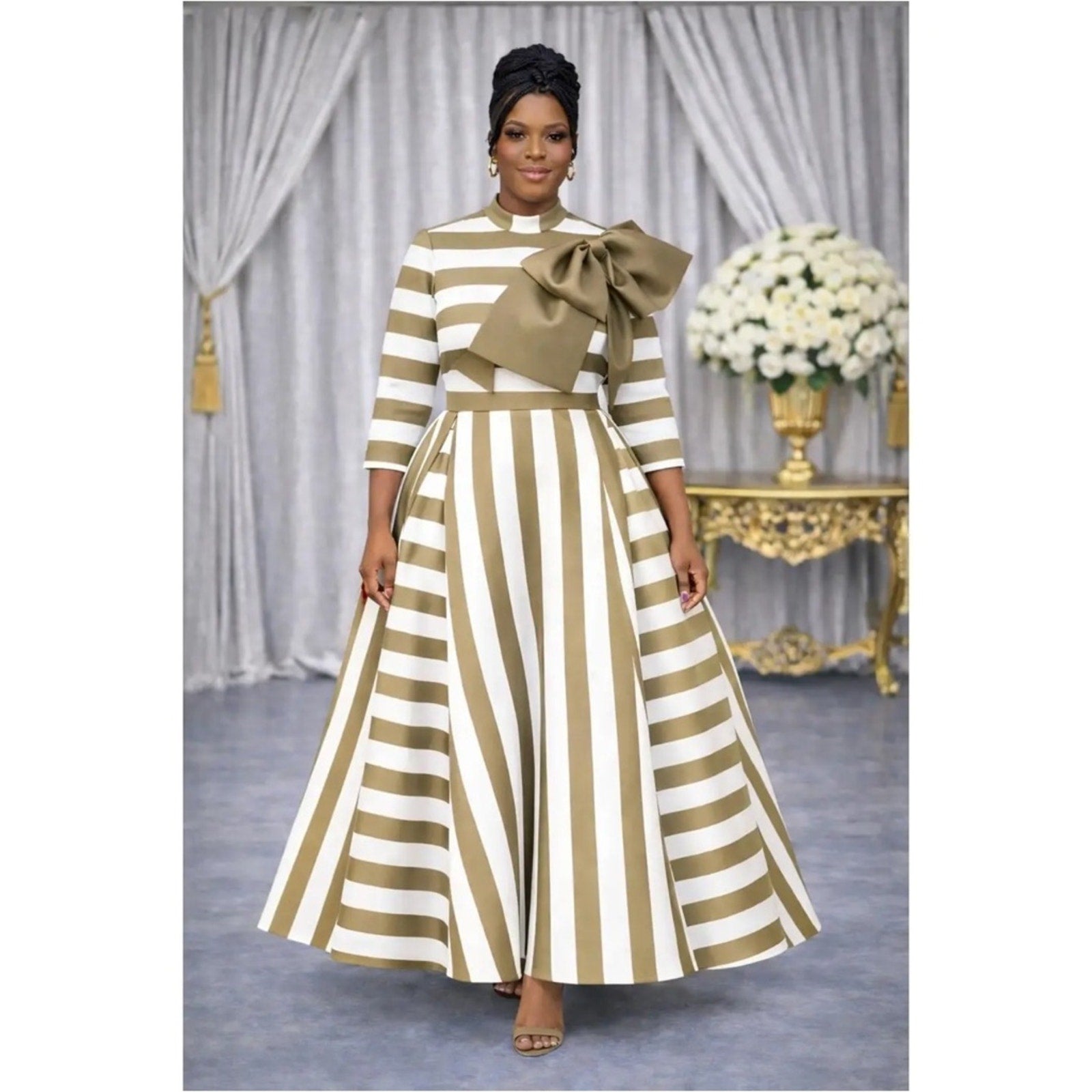 Woman wearing a gold and white striped dress with a large bow in a decorated room.