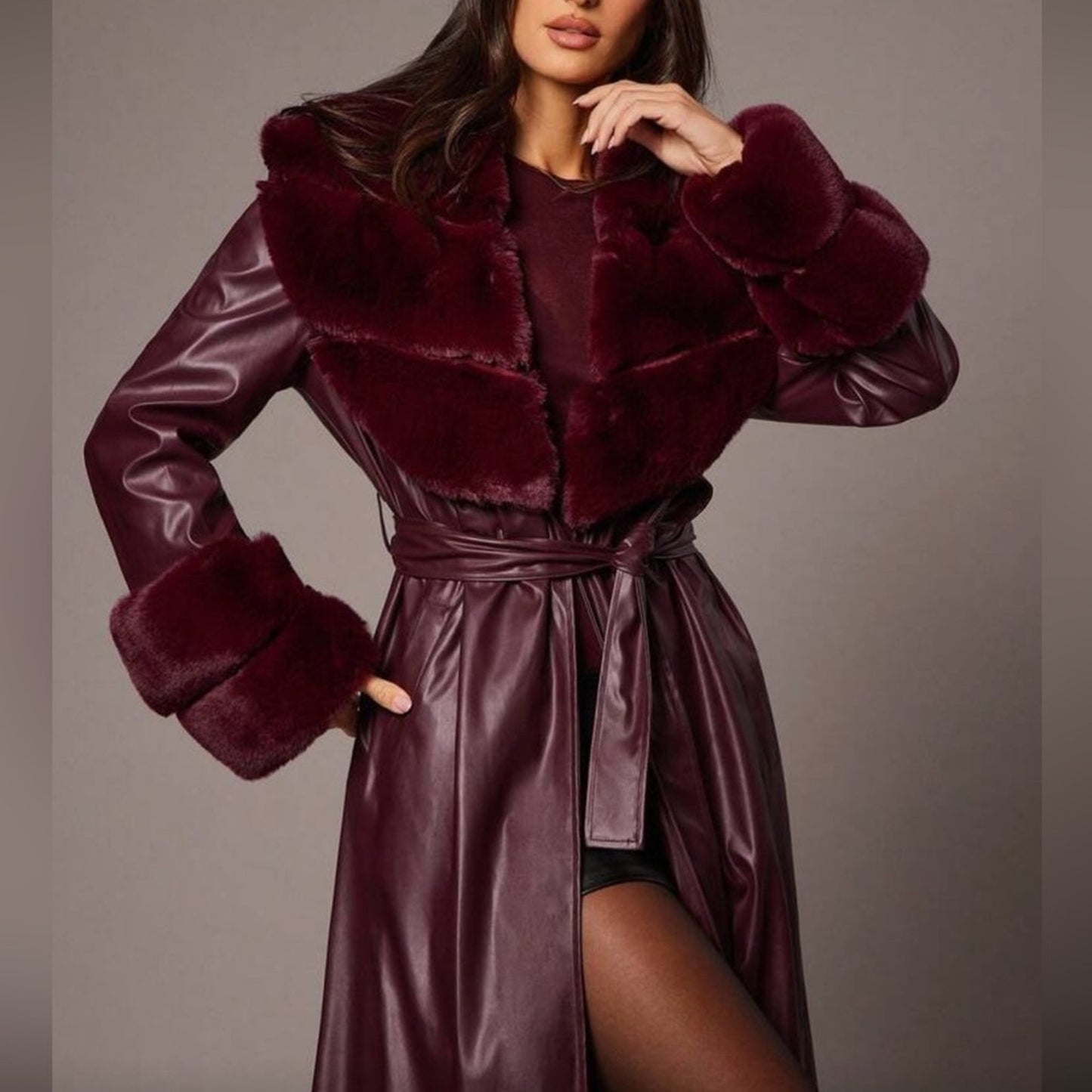 Woman wearing a burgundy fur-trimmed coat with a matching dress against a neutral background