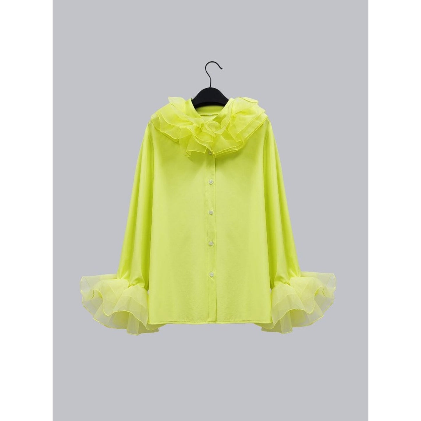 Yellow ruffled blouse on a hanger against a gray background