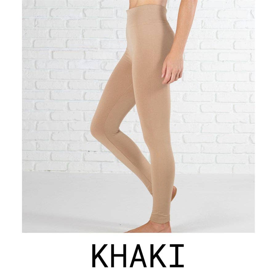 Khaki leggings worn by a person on a white brick wall background