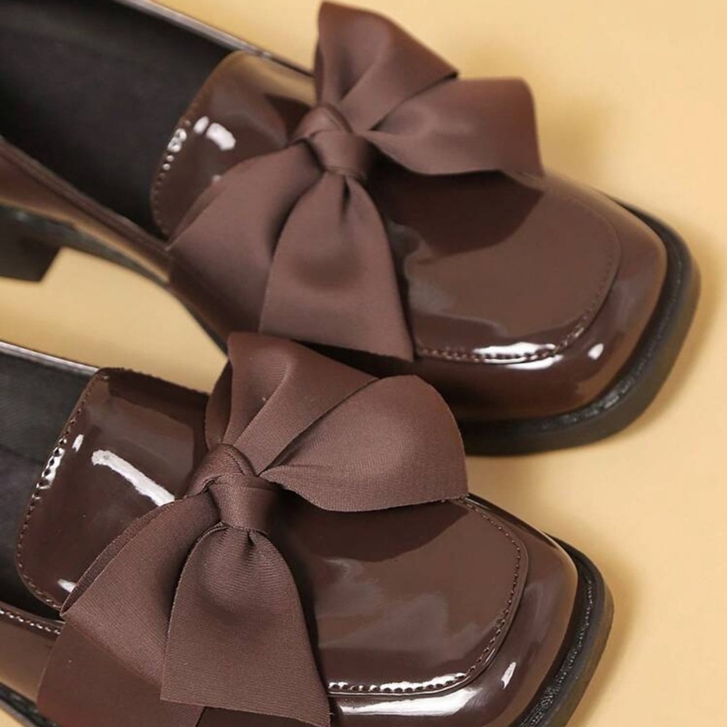 Brown shoes with large bows on a beige background