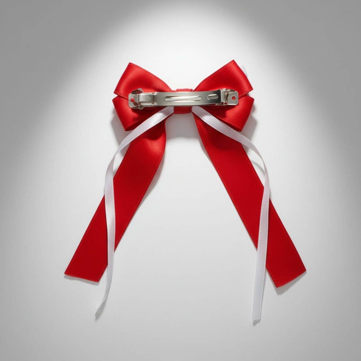 Red bow with a silver clip on a light gray background