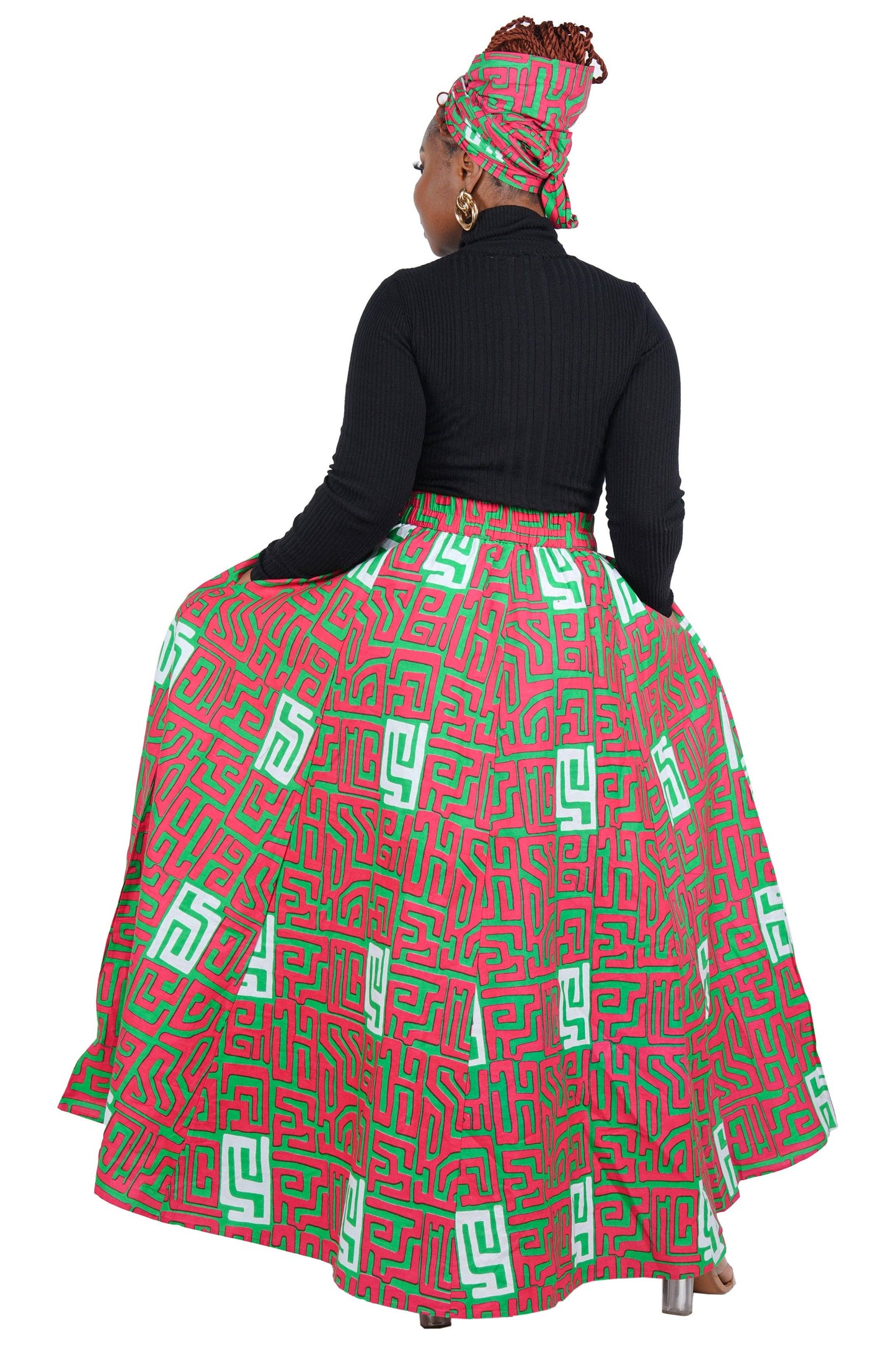 Woman wearing a red and green patterned skirt with a black top on a white background