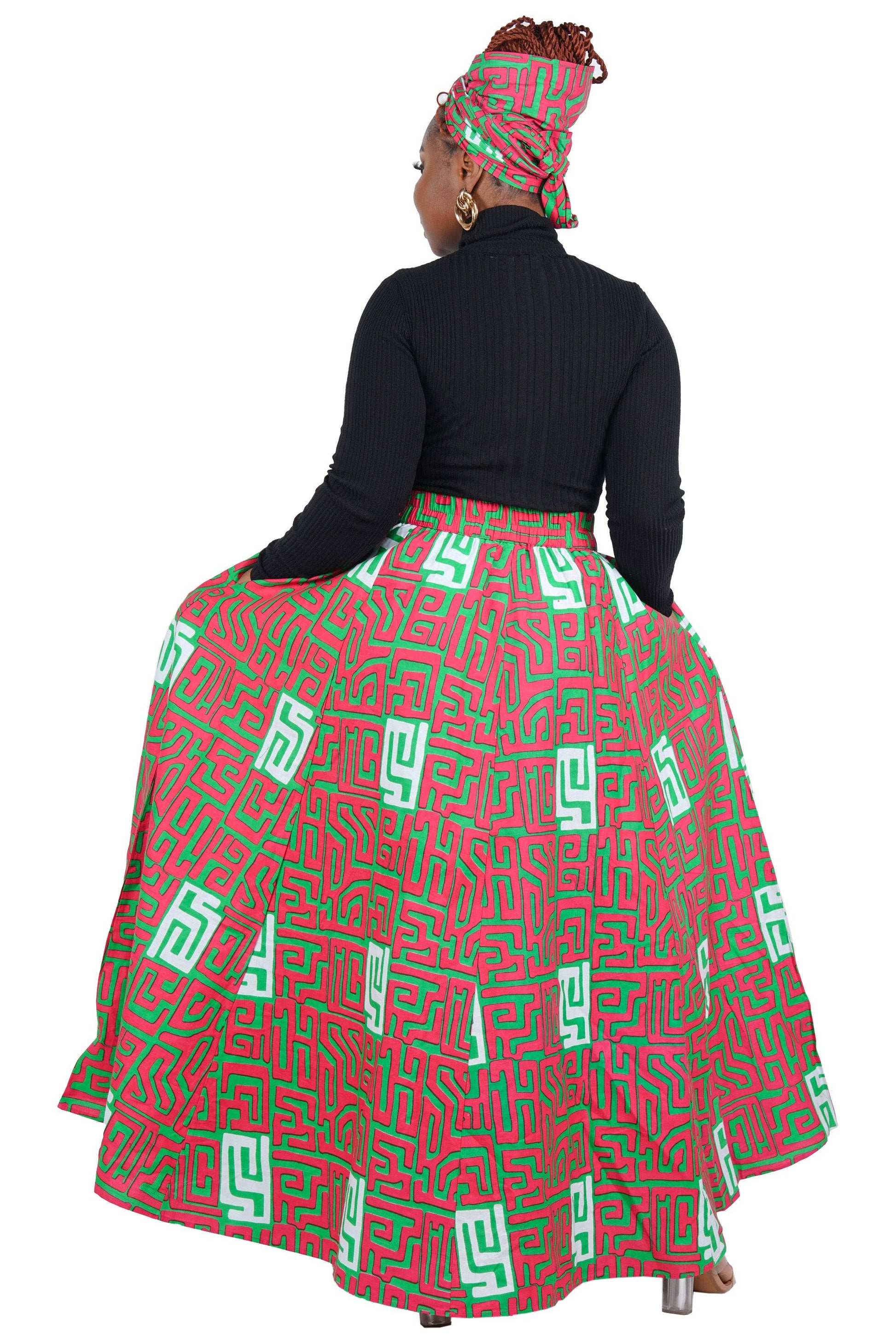 Woman wearing a red and green patterned skirt with a black top on a white background