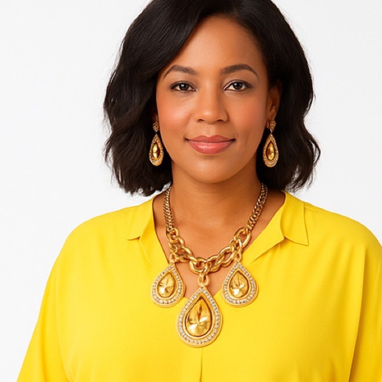 Woman wearing a gold necklace and earrings on a white background