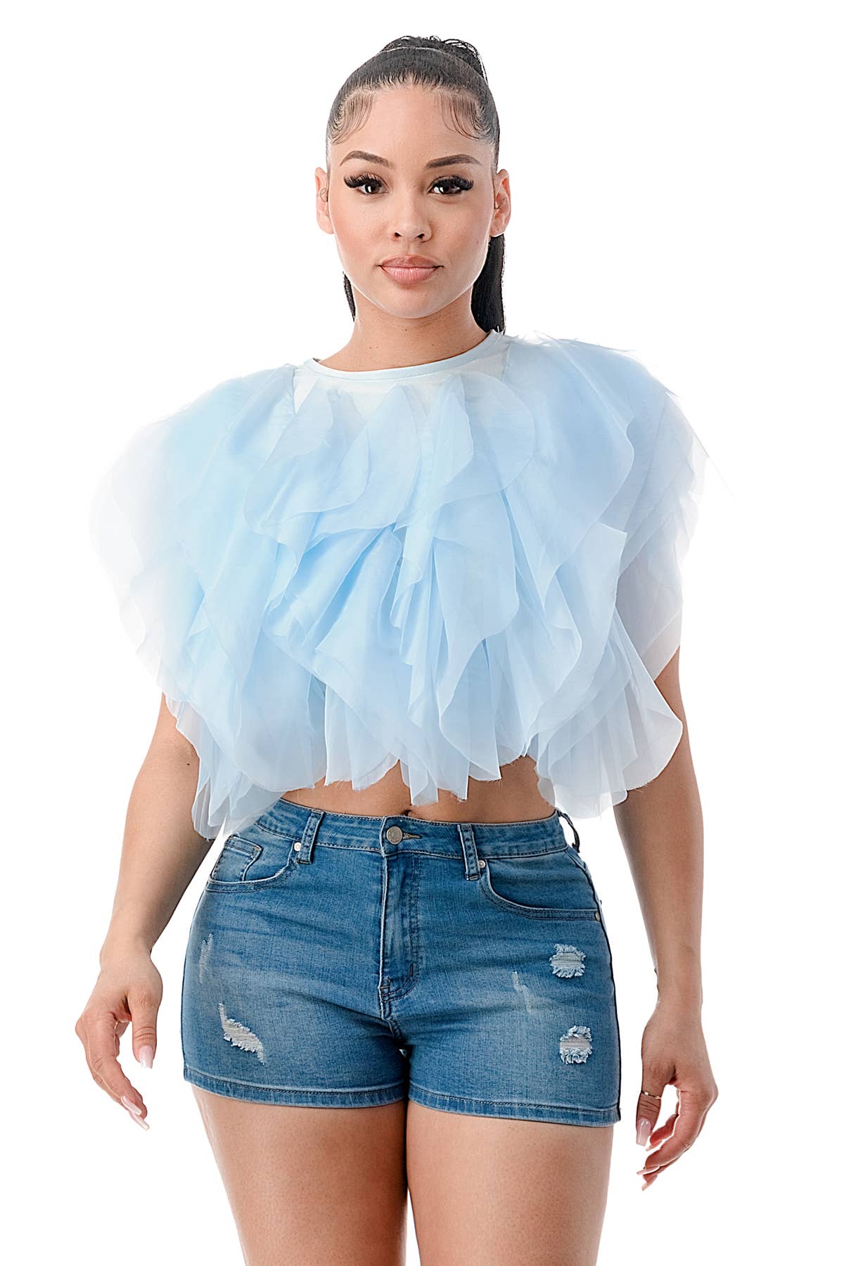 Woman wearing a light blue ruffled top and denim shorts on a white background