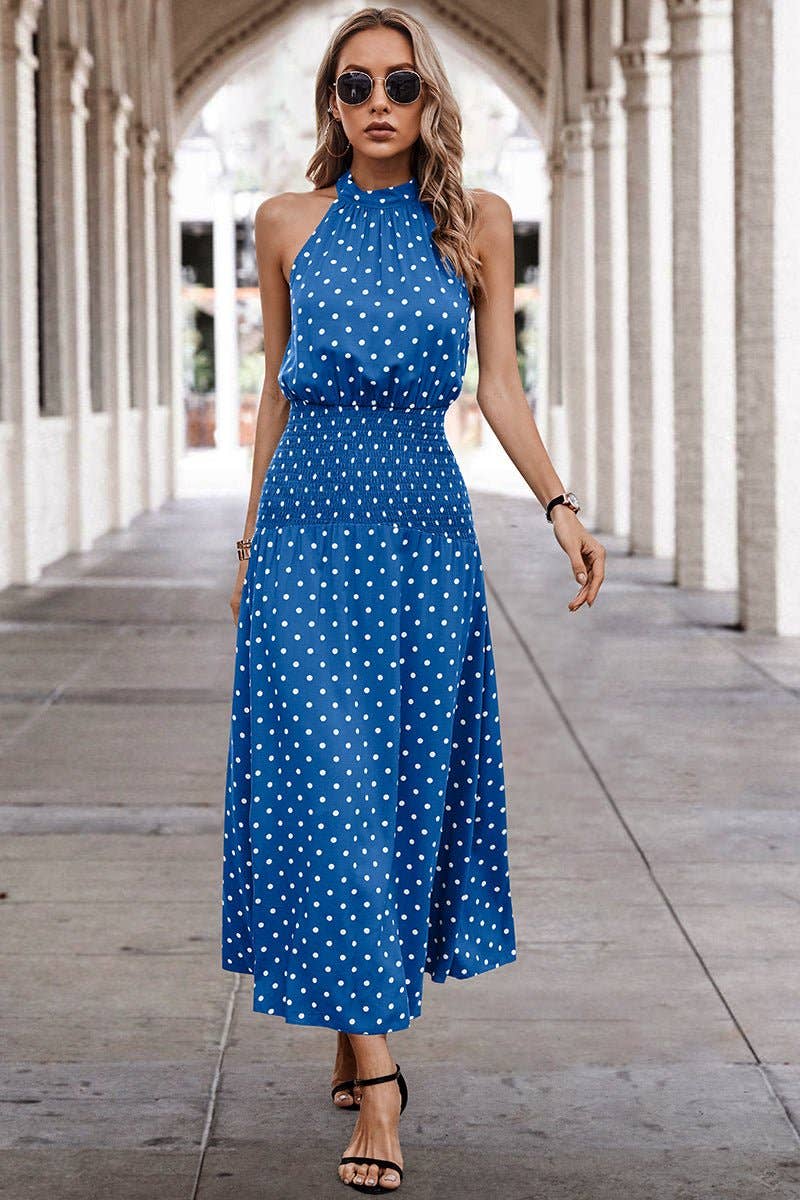 Woman wearing a blue polka dot dress walking under an archway.