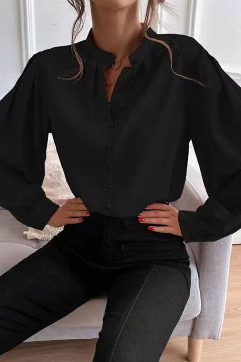 Person wearing a black blouse with puffed sleeves sitting on a chair.
