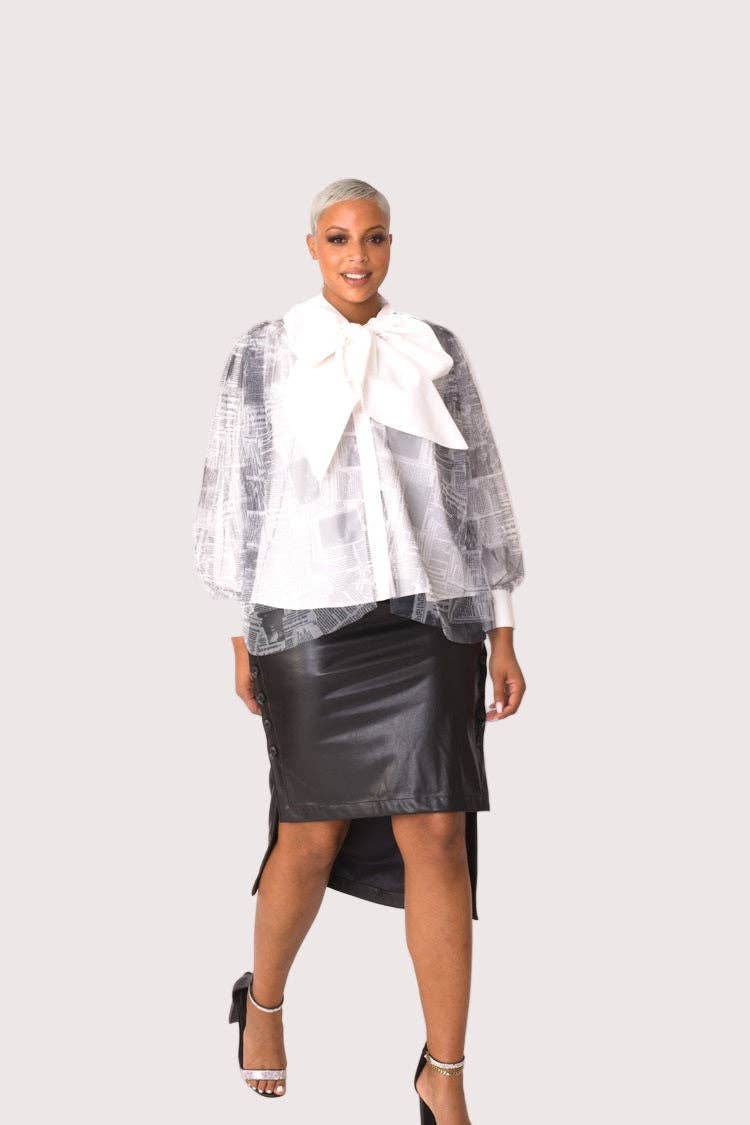 Woman wearing a white blouse with a large bow, transparent checkered jacket, and black leather skirt on a white background