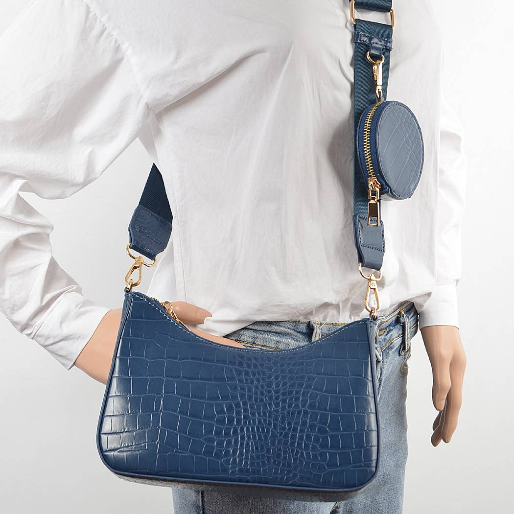 Person holding a blue handbag with a matching round pouch on a white background