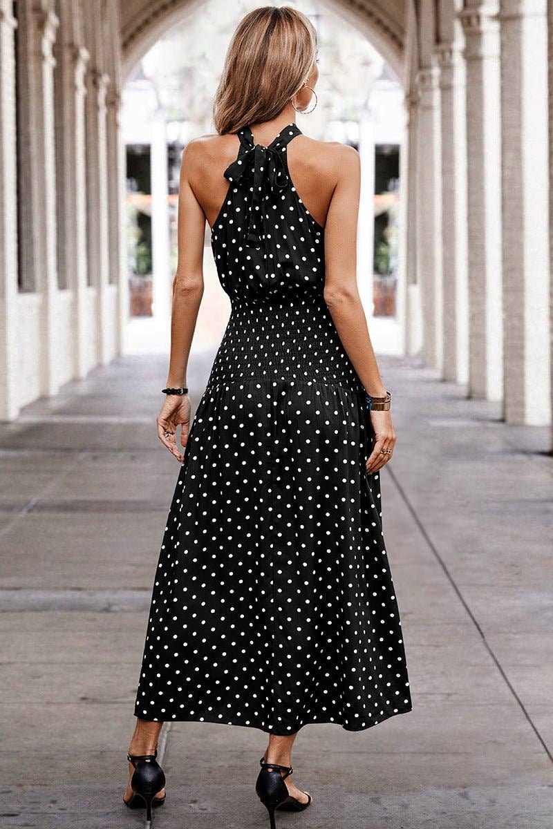 Woman wearing a black polka dot dress in an outdoor setting with columns.