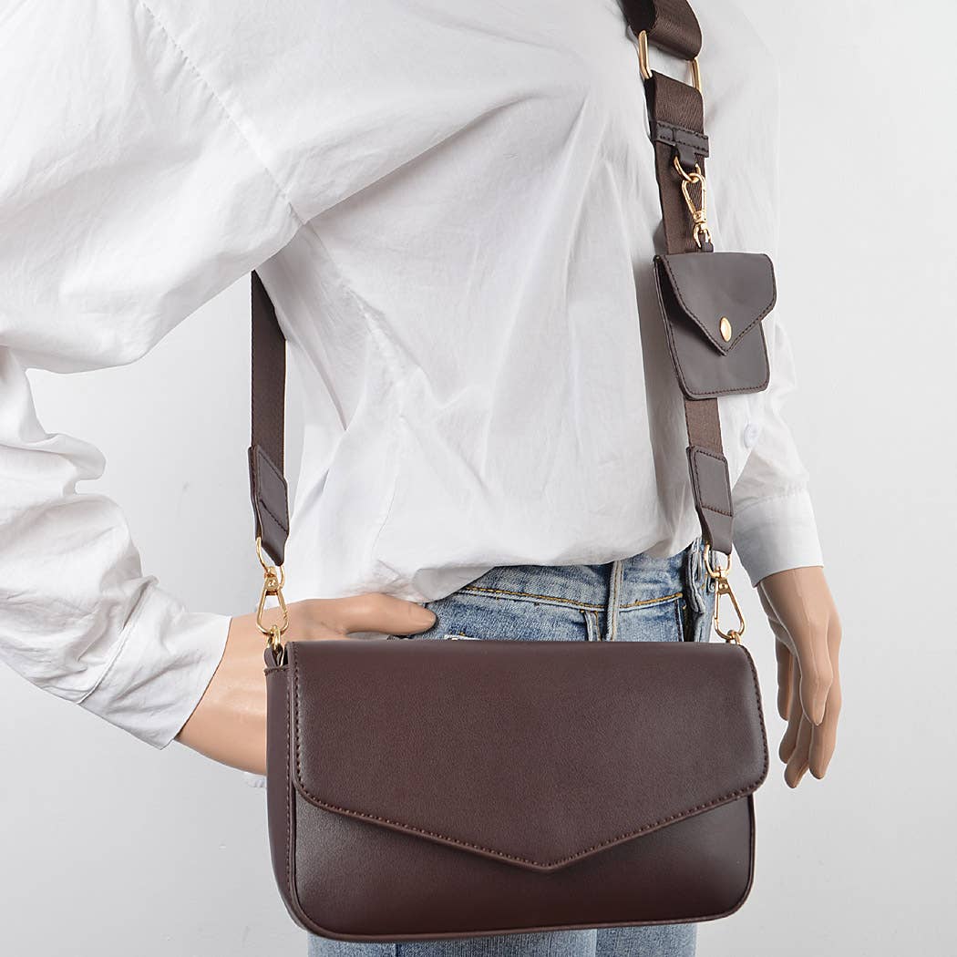 Brown leather crossbody bag worn by a person on a light gray background