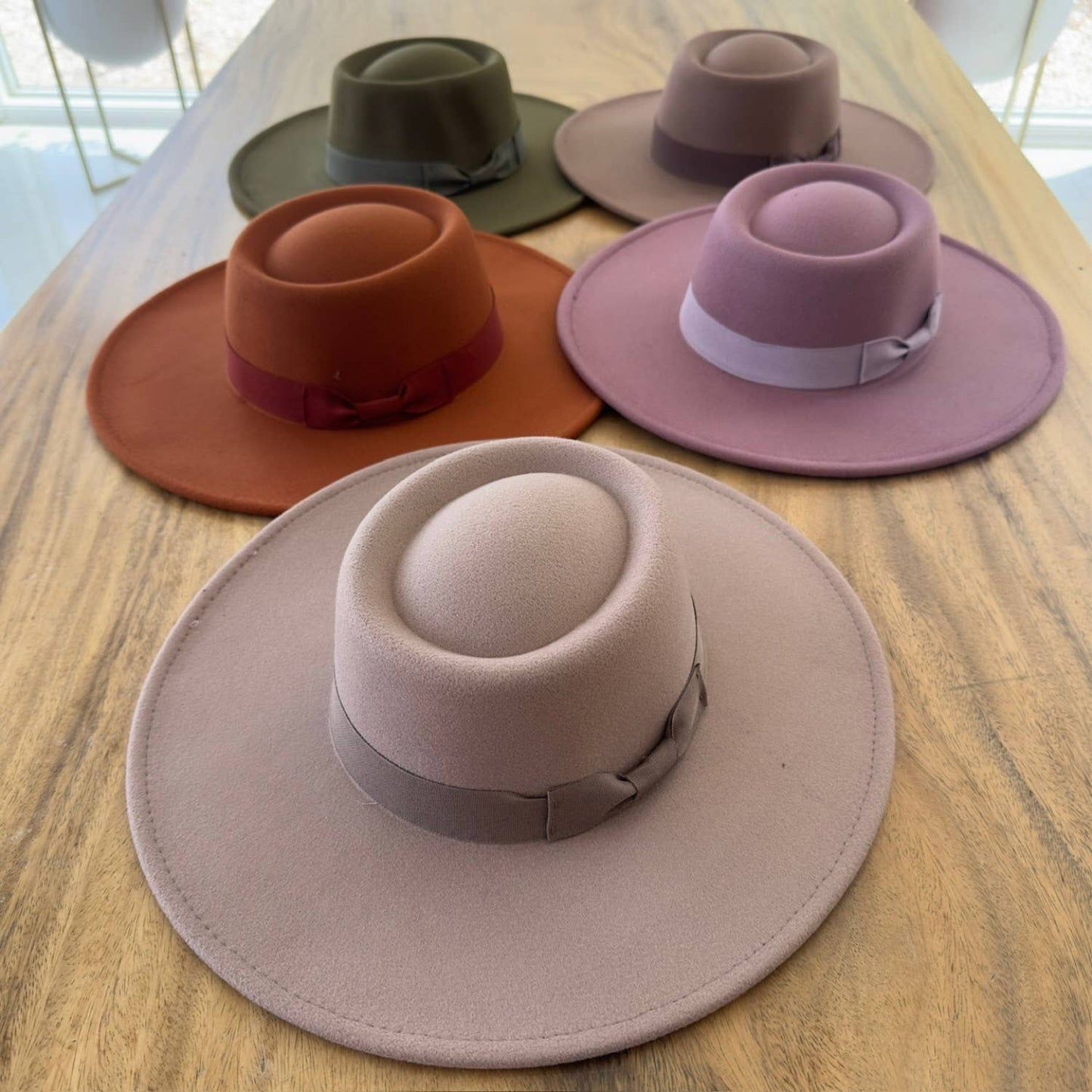 Five different colored hats arranged on a wooden surface.