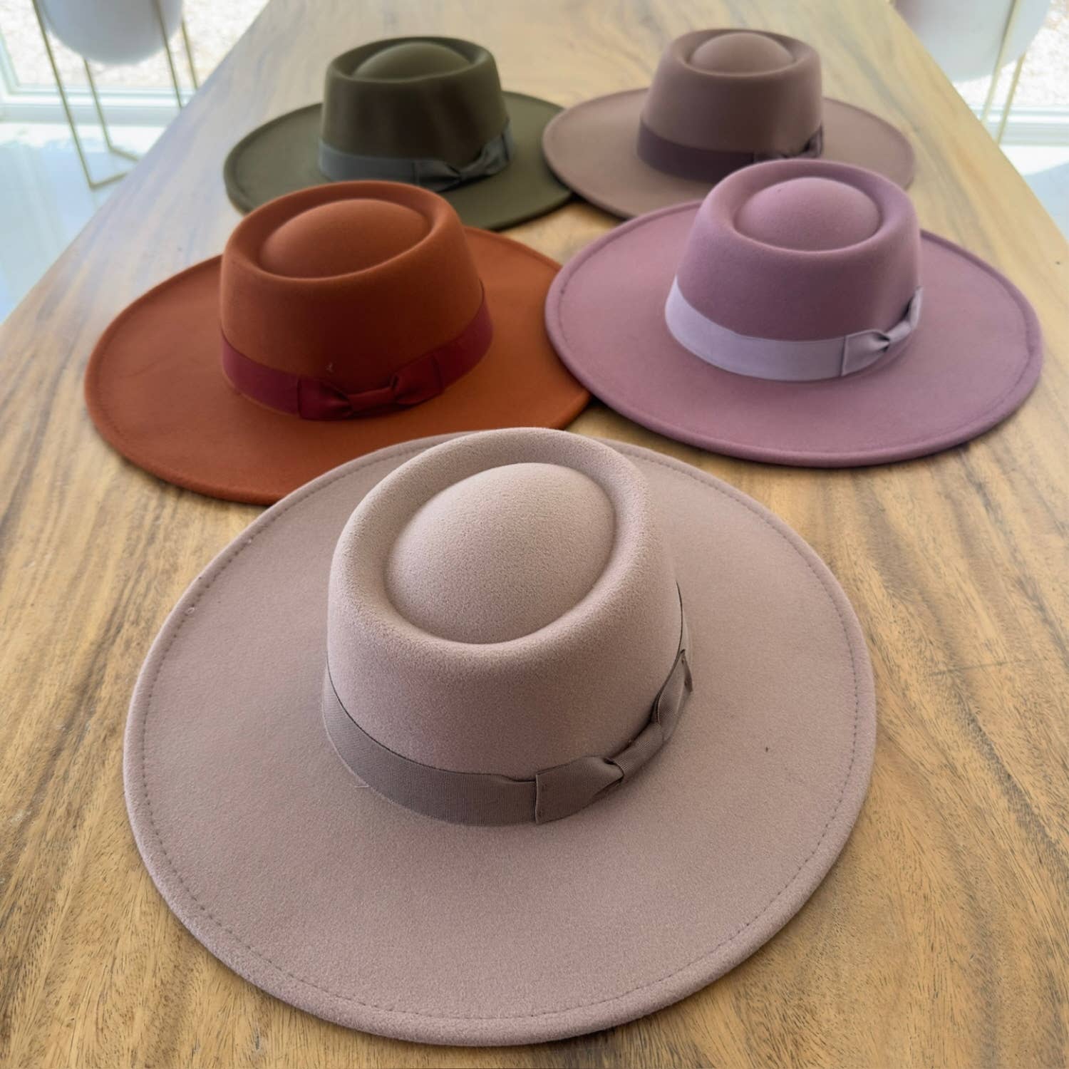 Five different colored hats arranged on a wooden surface.