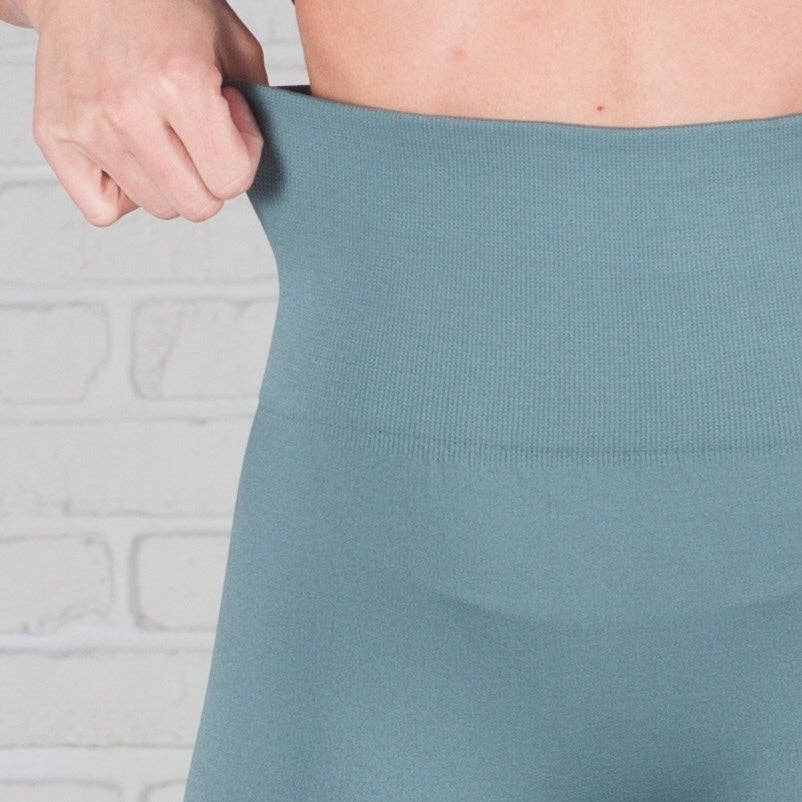 Person wearing a teal skirt with a neutral background