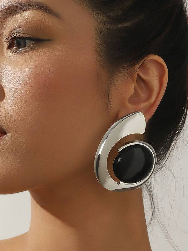 Close-up of a woman wearing a modern, silver earring with a black center.