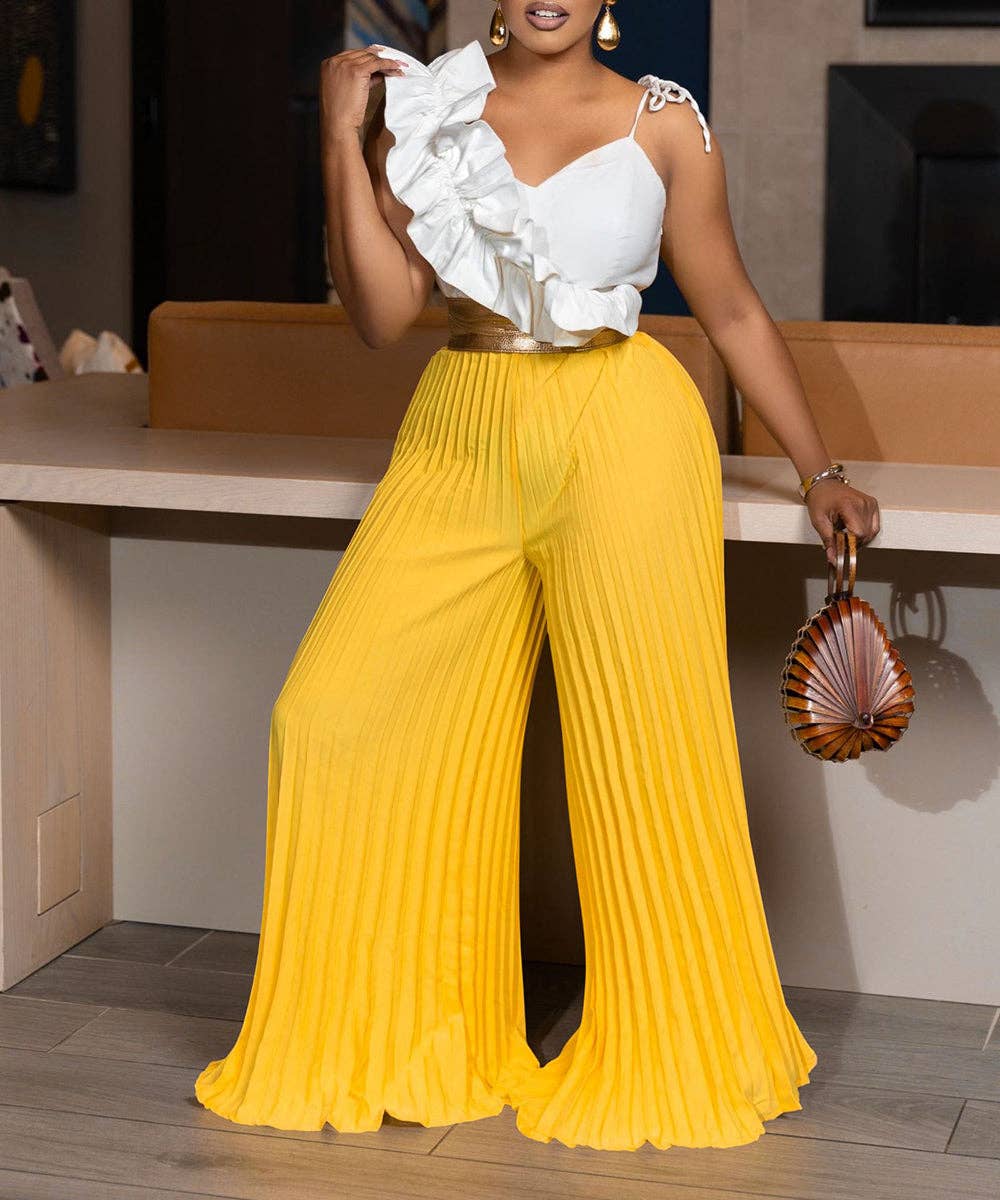 Woman wearing a white ruffled top and yellow pleated pants, holding a shell-shaped handbag.