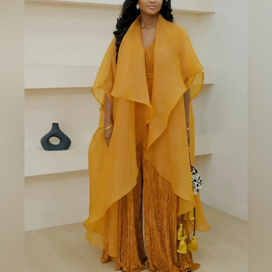 Woman wearing a mustard yellow outfit with a flowing top and patterned pants in an indoor setting.