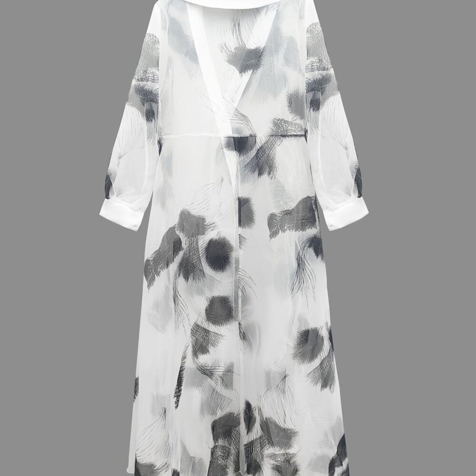 Long, light-colored dress with abstract black patterns on a gray background