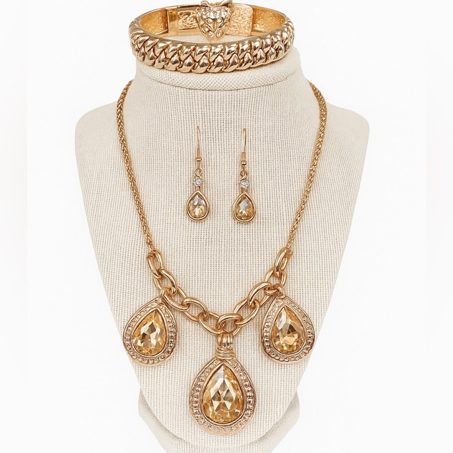 Gold jewelry set including necklace, earrings, and bracelet on a mannequin bust.