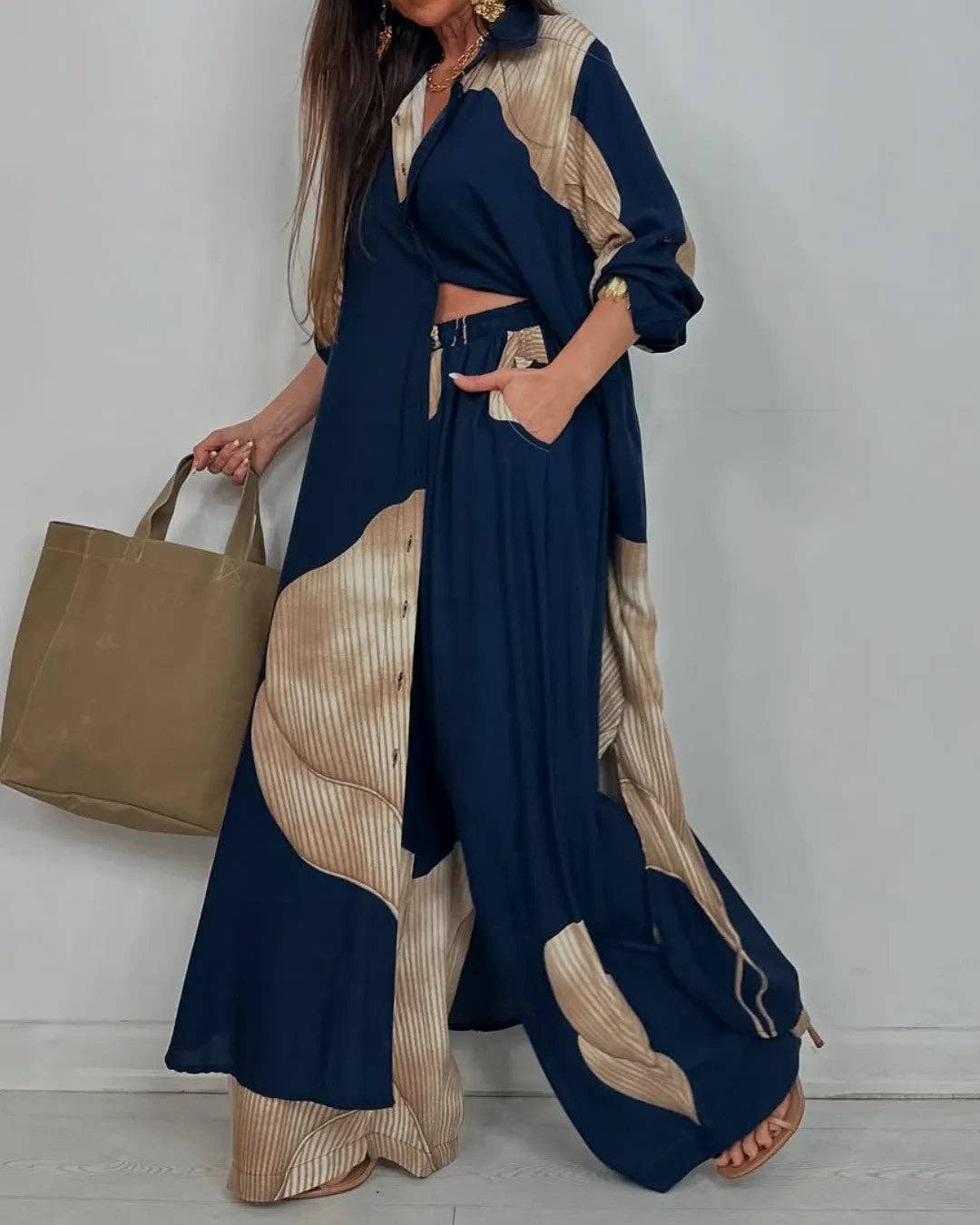 Woman wearing a navy and beige outfit with a brown bag against a white background