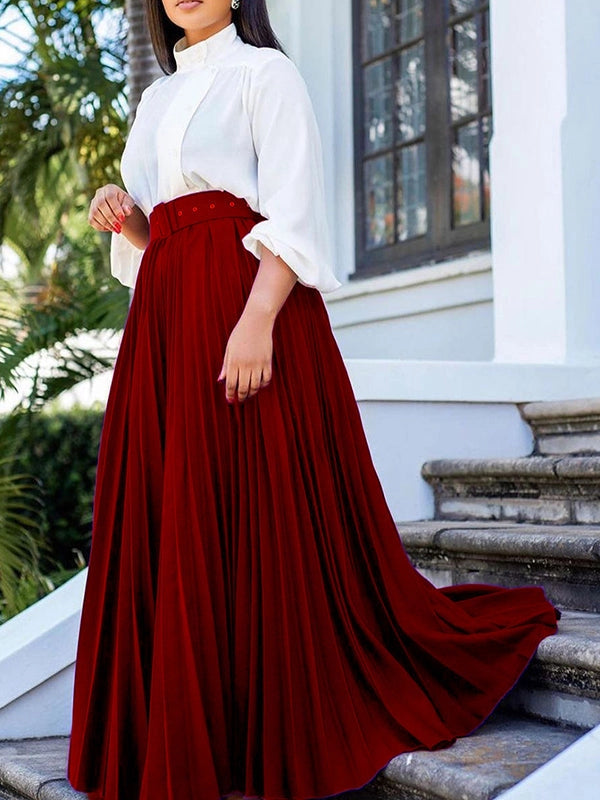 Woman wearing a white blouse and red skirt standing on steps outdoors.
