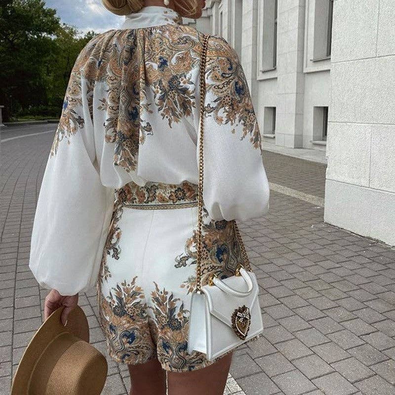 Woman in a floral outfit holding a white handbag on a sidewalk.