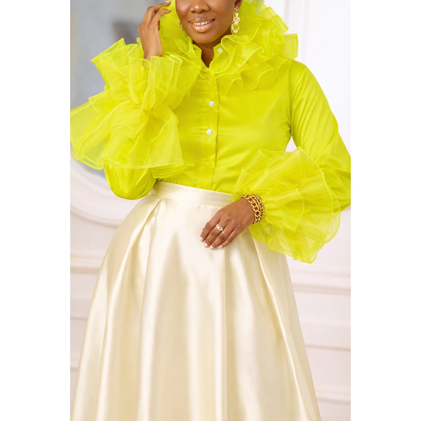 Person wearing a bright yellow ruffled blouse with a white background
