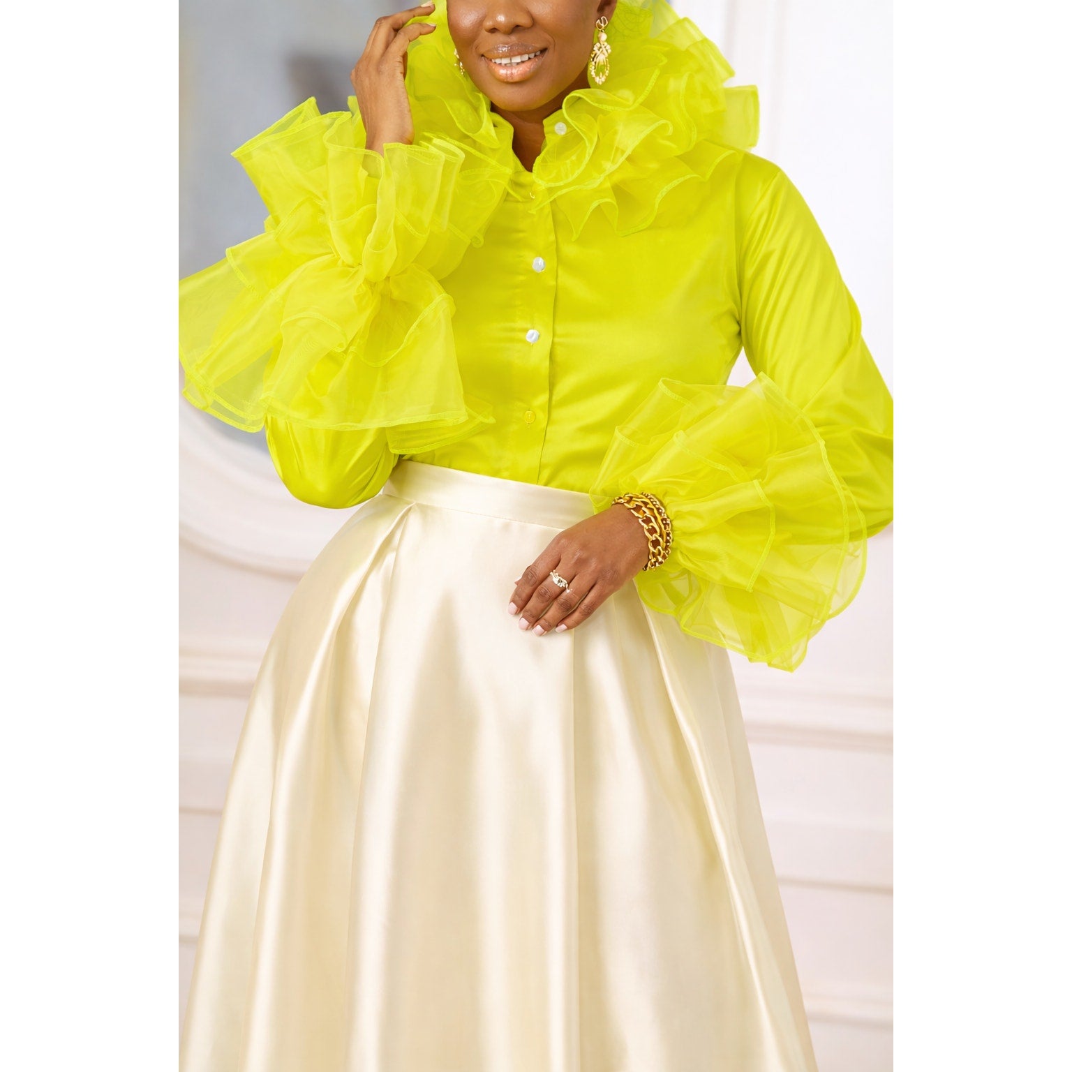 Person wearing a bright yellow ruffled blouse with a white background
