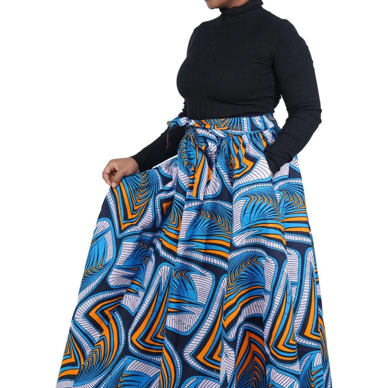 Person wearing a blue and orange patterned skirt with a black top on a white background