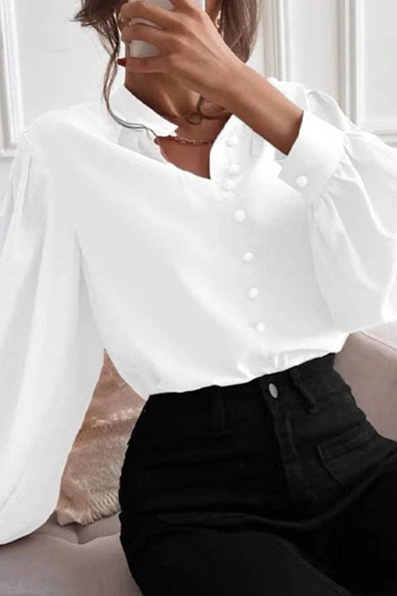 Person wearing a white blouse with long sleeves and black pants.