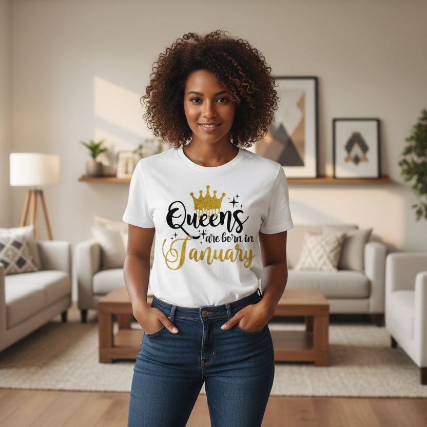 White t-shirt with 'Queens are born in January' text and gold crown graphic on a light wooden surface.