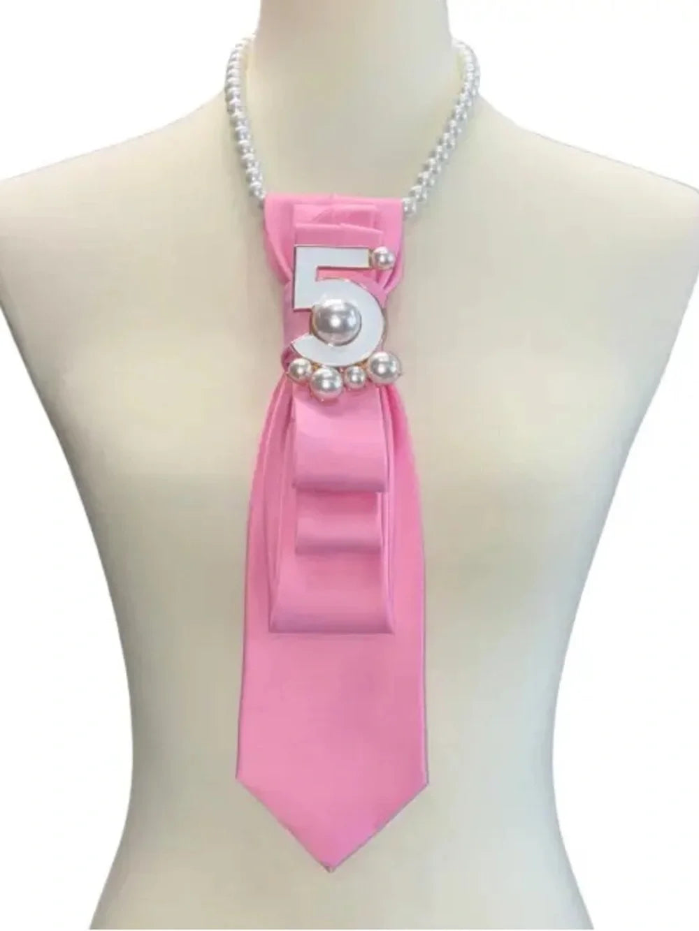 Mannequin wearing a pink ribbon with number 5 and pearls on a white background