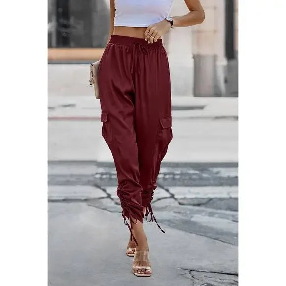 Person wearing burgundy cargo pants on a blurred street background