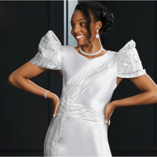 Woman wearing a white beaded dress with puffed sleeves against a black background